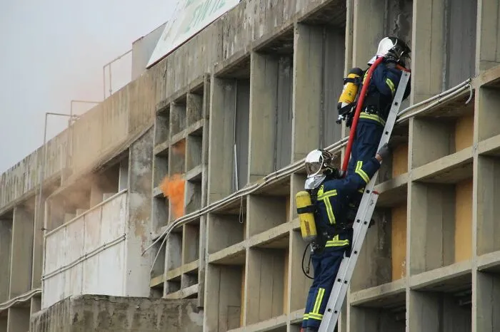 Firefighters on a ladder near a burning building, highlighting facts that make a difference in an emergency.