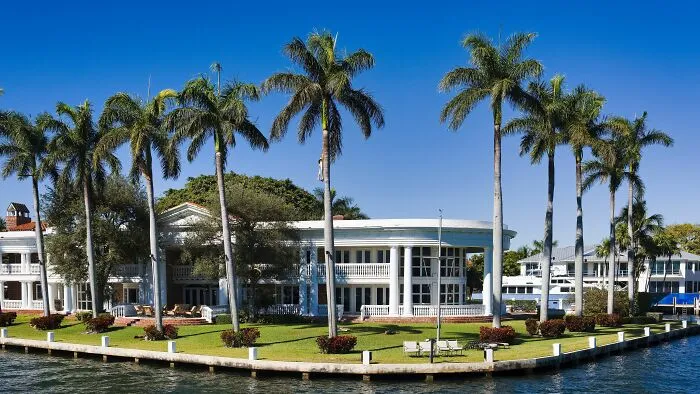 A luxurious waterfront mansion with tall palm trees, demonstrating how rich people live