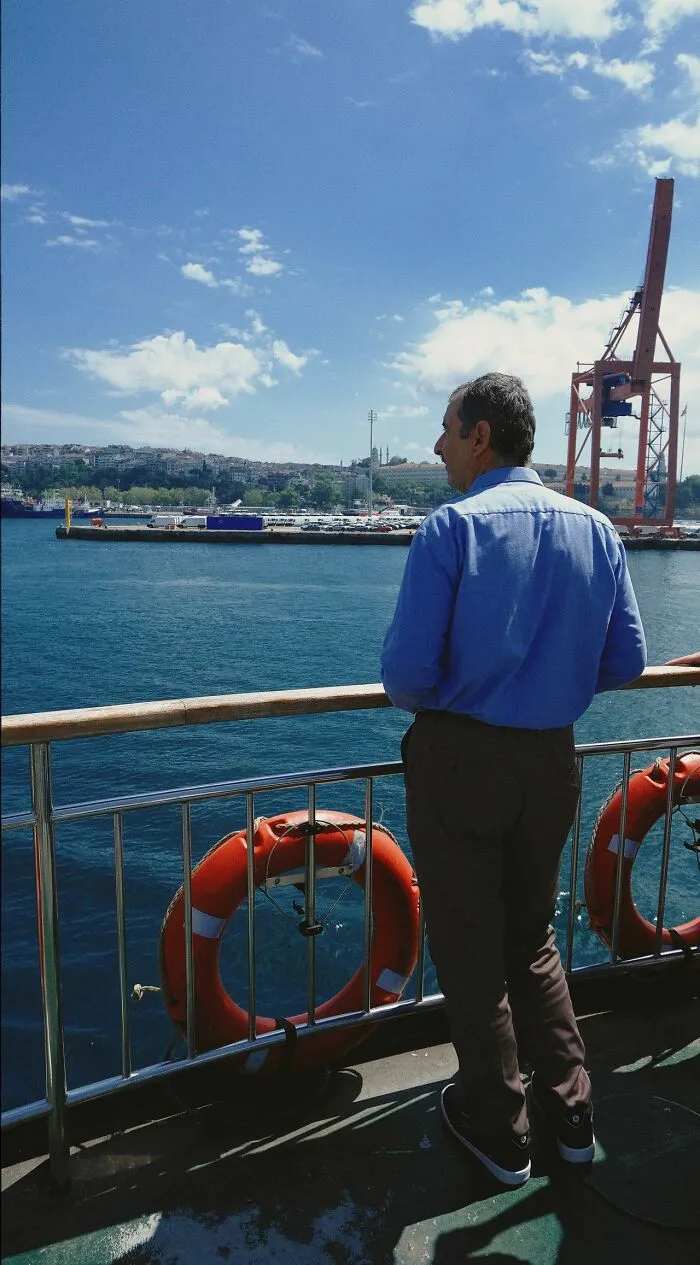 A man looking at the sea from a boat, prepared with lifebuoys for any emergency situation.