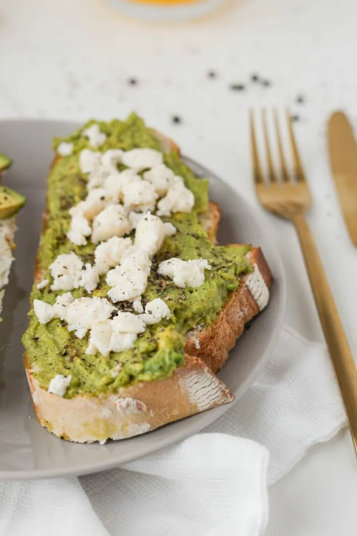 A slice of avocado toast topped with feta cheese on a plate, reflecting middle-class life trends