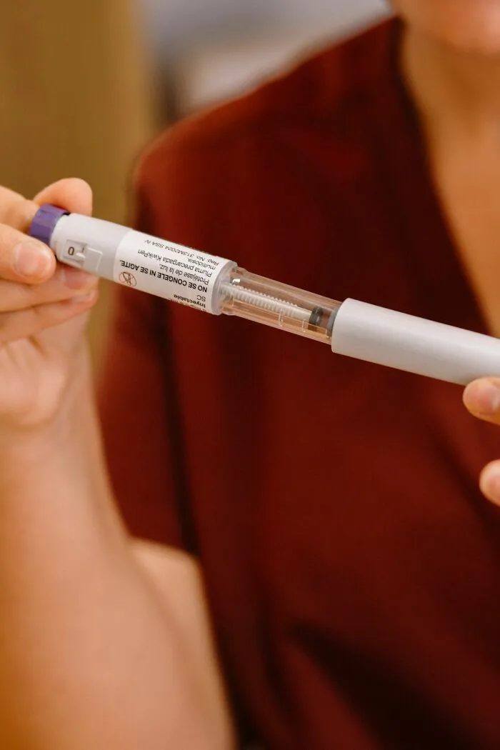 Hands holding an adrenaline auto-injector used in an emergency