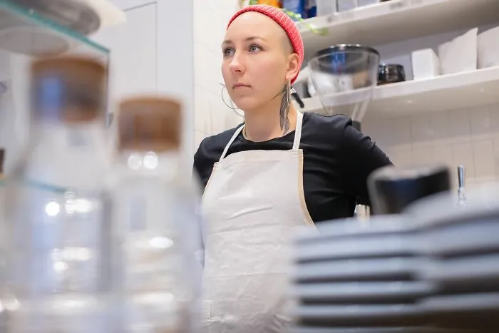 Restaurant worker in apron looking serious behind counter