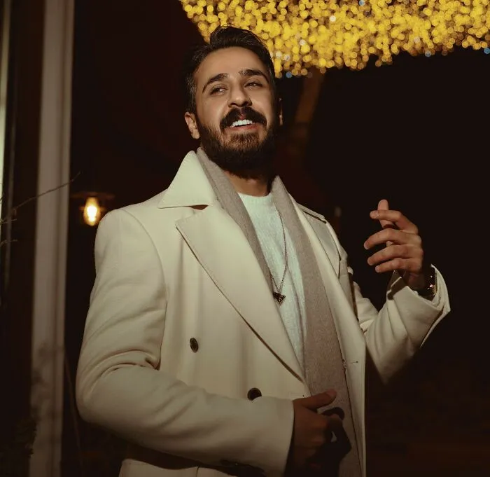 A smiling man in an elegant white coat, depicting how rich people try to look like they have class