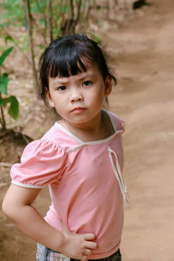 A young girl in a pink shirt standing with hands on hips, showcasing childhood attitude in middle-class life