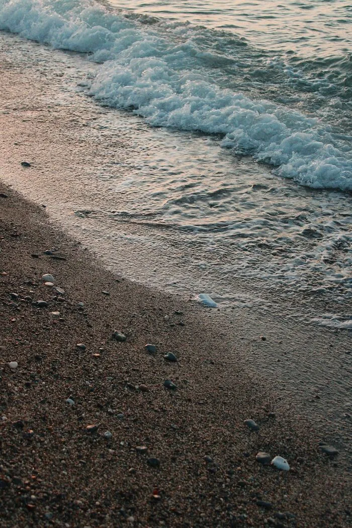 Ocean tide washing over a dark sandy beach, showing coastal safety facts that could make a huge difference in an emergency