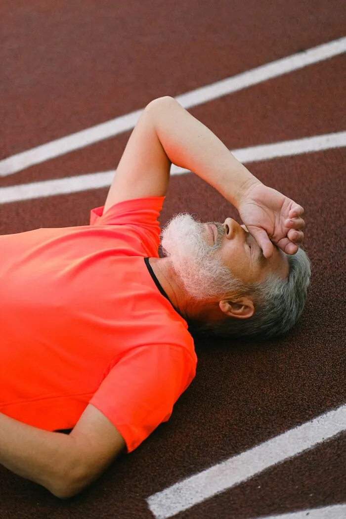 Senior man lying on track feeling exhausted, representing emergency facts about heart stroke