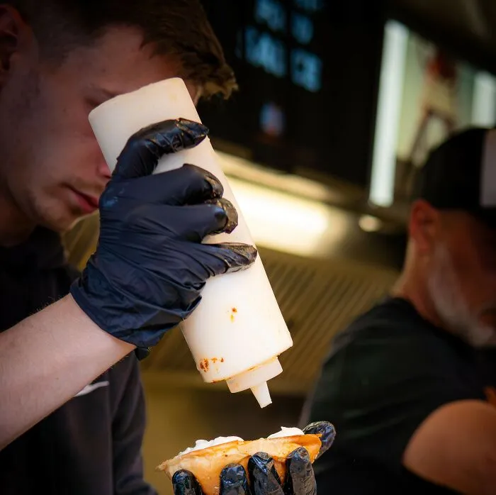 Restaurant chef squeezing sauce on food wearing black gloves