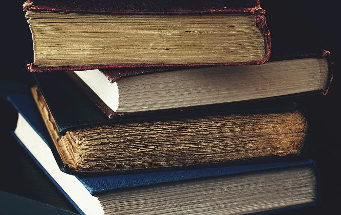 A stack of old vintage books with worn covers, illustrating what truly cultured rich people read