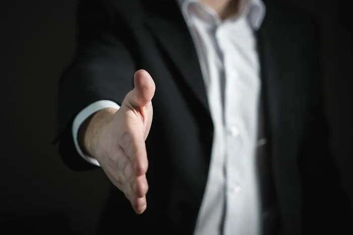A businessman extending his hand for a handshake, representing corporate scandals