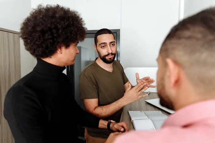 Group discussion with man explaining clever insults in social setting