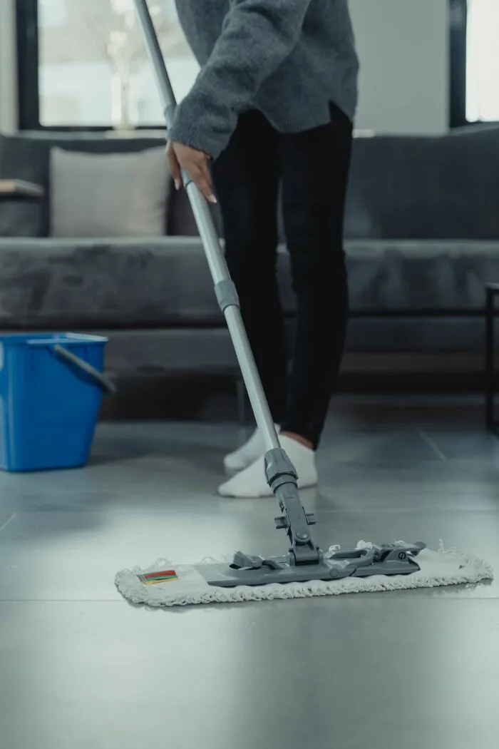 A person mopping a grey tiled floor, illustrating everyday chores in a middle-class life