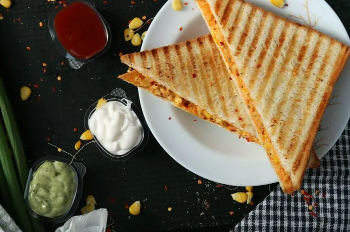 Toasted sandwiches served on a plate with dipping sauces