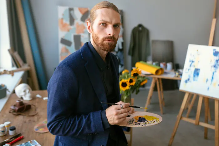 An artist holding a palette looks thoughtfully forward, capturing the reflection typical of divorced people