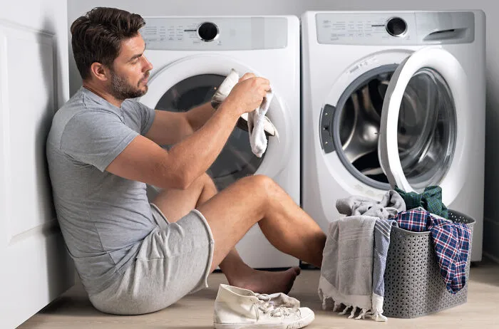 Man loading laundry into washing machine in modern laundry room
