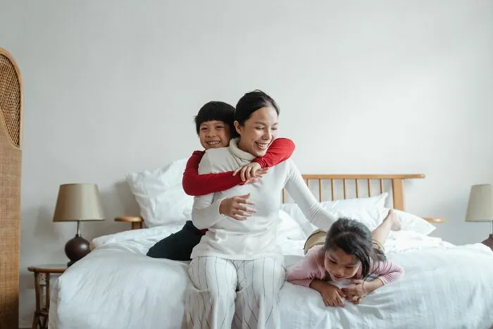 A happy mother with her children on a bed, finding peace after marriages collapsed