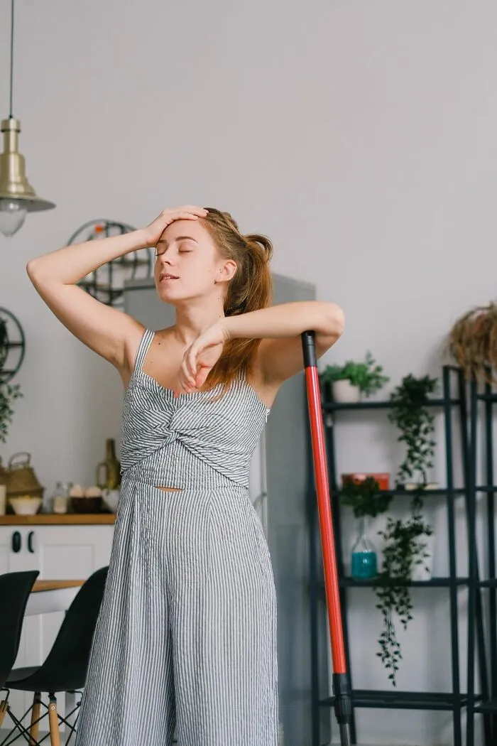 A tired woman rests on a mop in her kitchen, showing the exhaustion that can make marriages collapsed