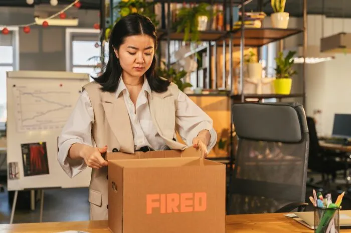Sad woman packing her belongings after being fired, a reminder of relationship revenge stories.