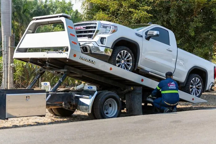 A white truck is loaded onto a flatbed tow truck, showing potential for relationship revenge.