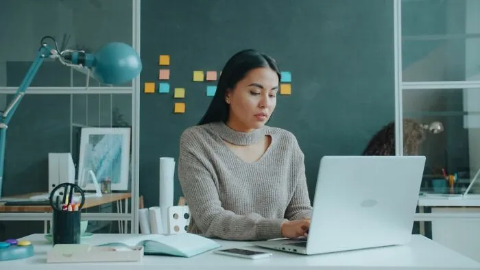 A woman working on a laptop, brainstorming relationship revenge stories