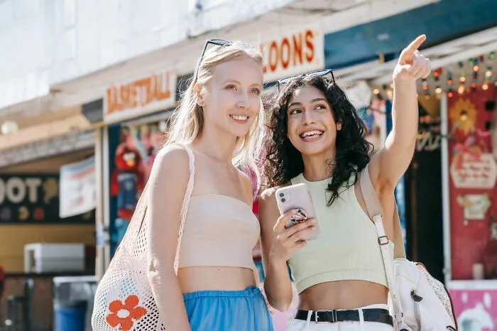 Two young women smile and point into the distance, illustrating an idea for relationship revenge.
