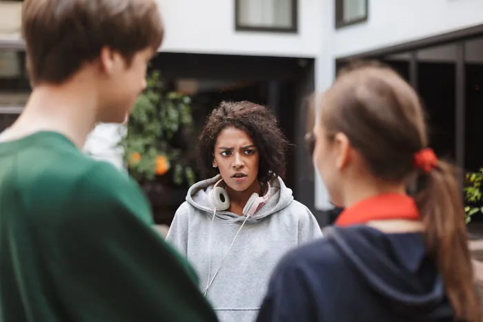 Young woman looking upset in group conversation about clever insults