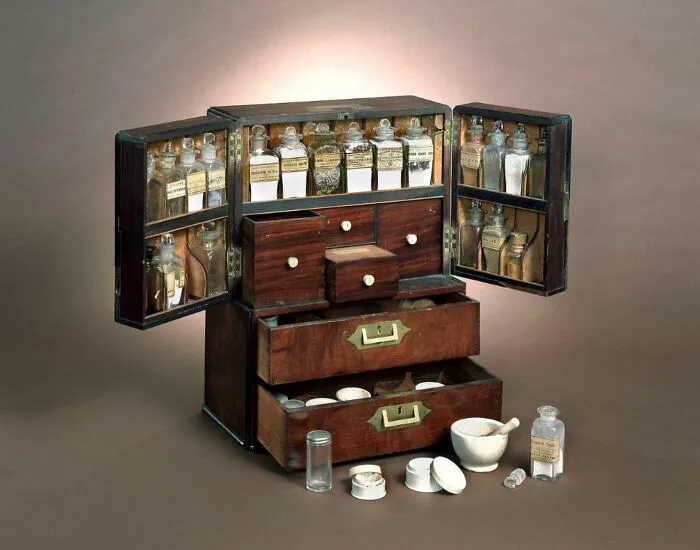 A wooden medicine chest from medical history, filled with various glass apothecary bottles.