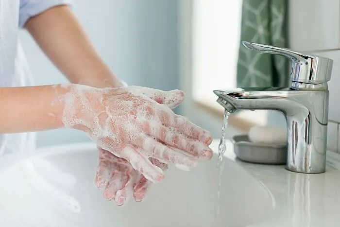 Close-up of hands washing with soap foam by sink