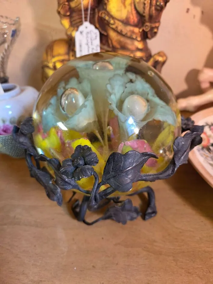 Floral glass paperweight on a metal stand showcased in thrift finds.