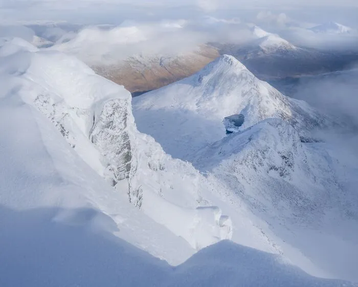 Snow covered mountain peaks under a cloudy sky showcasing natural landscape photography.