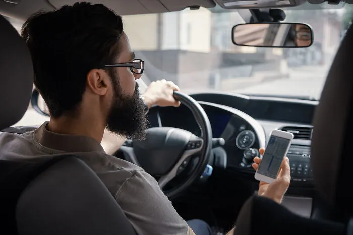 A man driving a car holding a phone, reacting instantly to strange words that activated fight-or-flight.