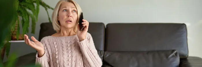An anxious mother on the phone in her living room, displaying typical signs of helicopter parenting.