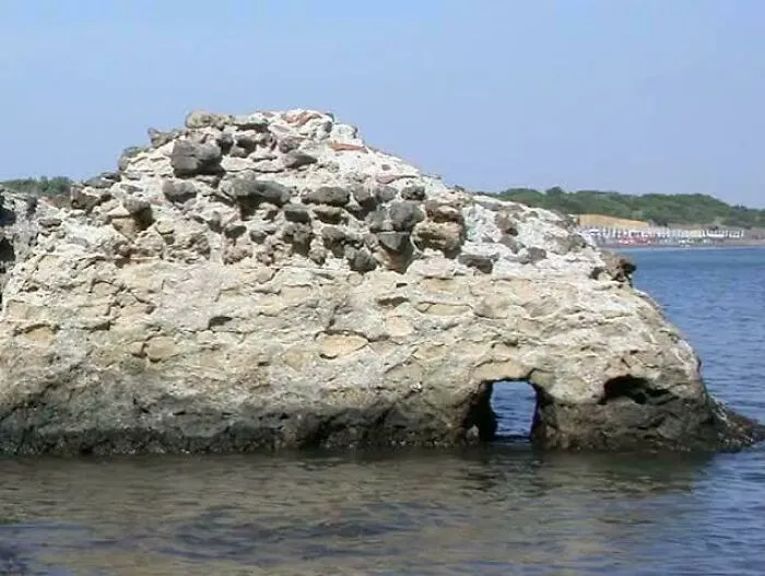 Ancient stone structure partially submerged in water with a small arch