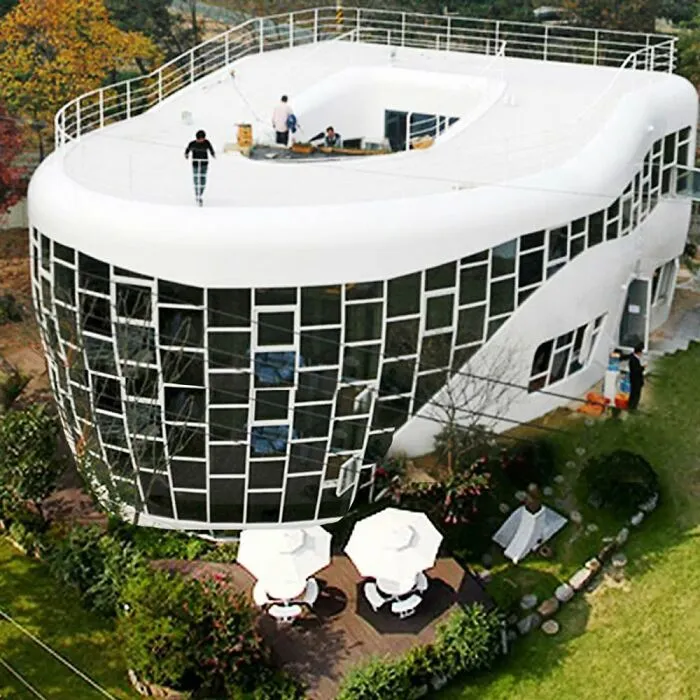 White futuristic building with irregular windows and rooftop terrace under construction