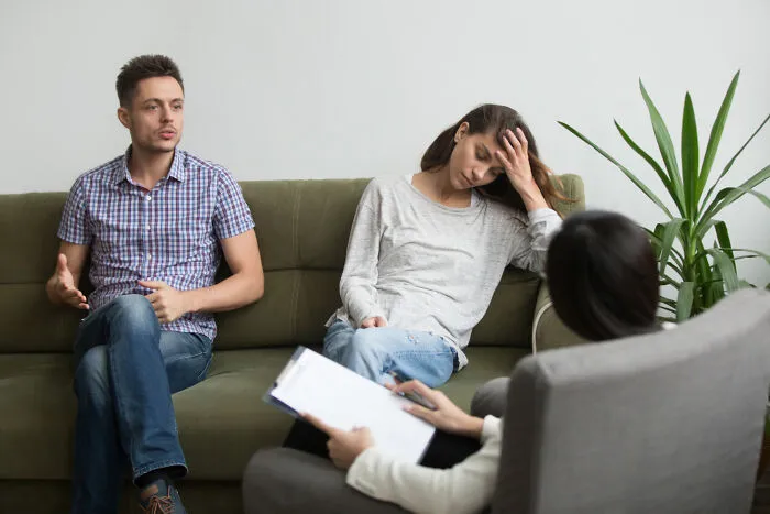 A couple sitting on a couch during therapy, reflecting emotional strain in divorce stories.