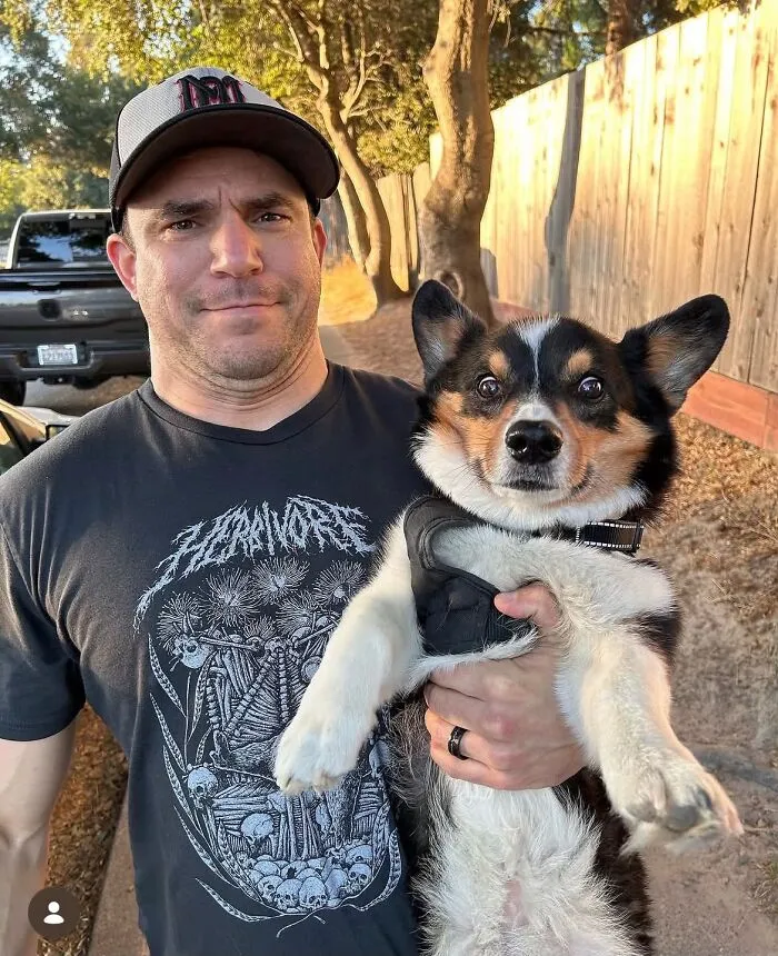 Man smiling next to his Corgi dog with a similar facial expression, showing pets who look like their owners.