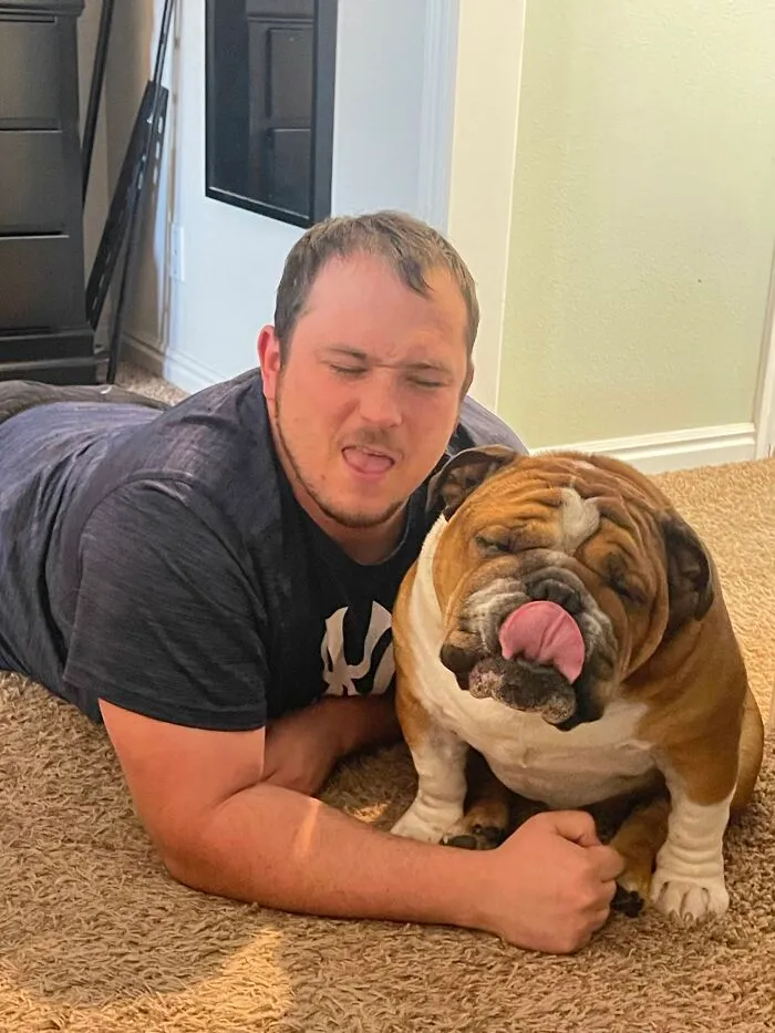 A man and his bulldog lying on the floor making a silly face, depicting pets that look like their owners.