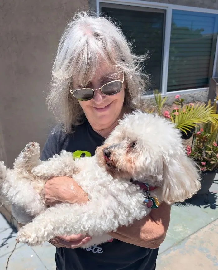 Woman with grey hair matching her white fluffy pet dog