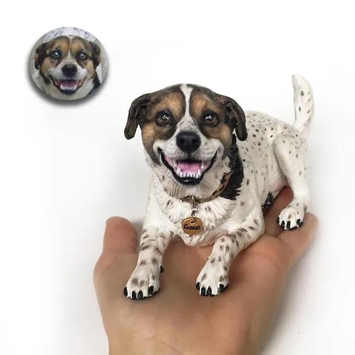 A happy, smiling dog figure resting in a hand, an example of hyperrealistic sculptures of pets made from photos.