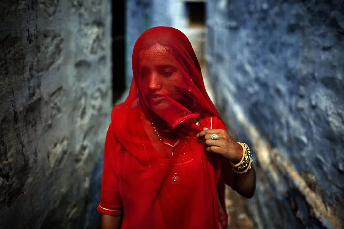 Woman in red veil with bangles walking in narrow alley, best pics Siena International Photo Awards 2026