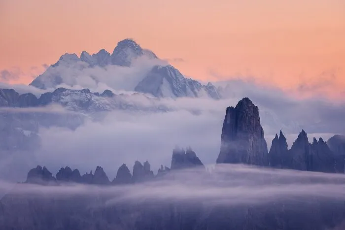 Jagged mountain peaks rising above low clouds at sunset in Natural Landscape Photography Awards 2026.