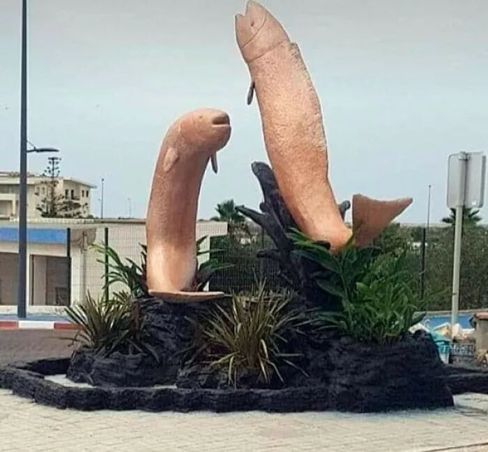 A bizarre example of public art featuring two phallic-looking fish sculptures by a coastal road.