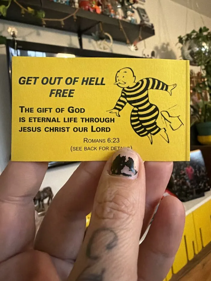 A yellow religious tract styled like a Monopoly card held up, illustrating a unique found paper