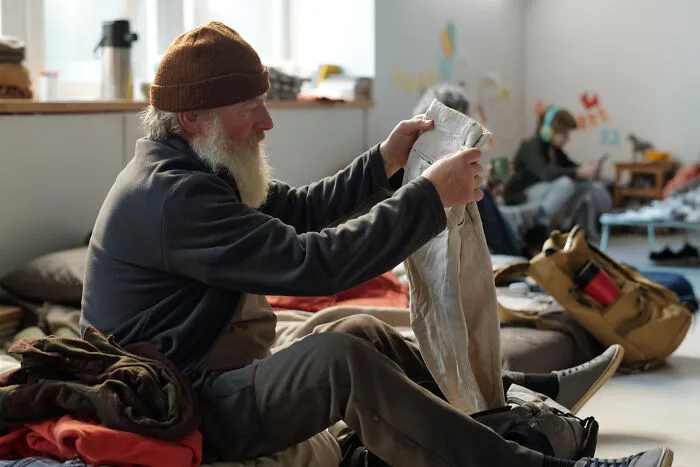 An older man looking through donated clothing, reflecting emotional and real stories of life.