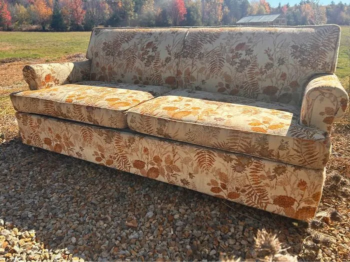 Vintage floral patterned thrift store sofa on gravel outdoors