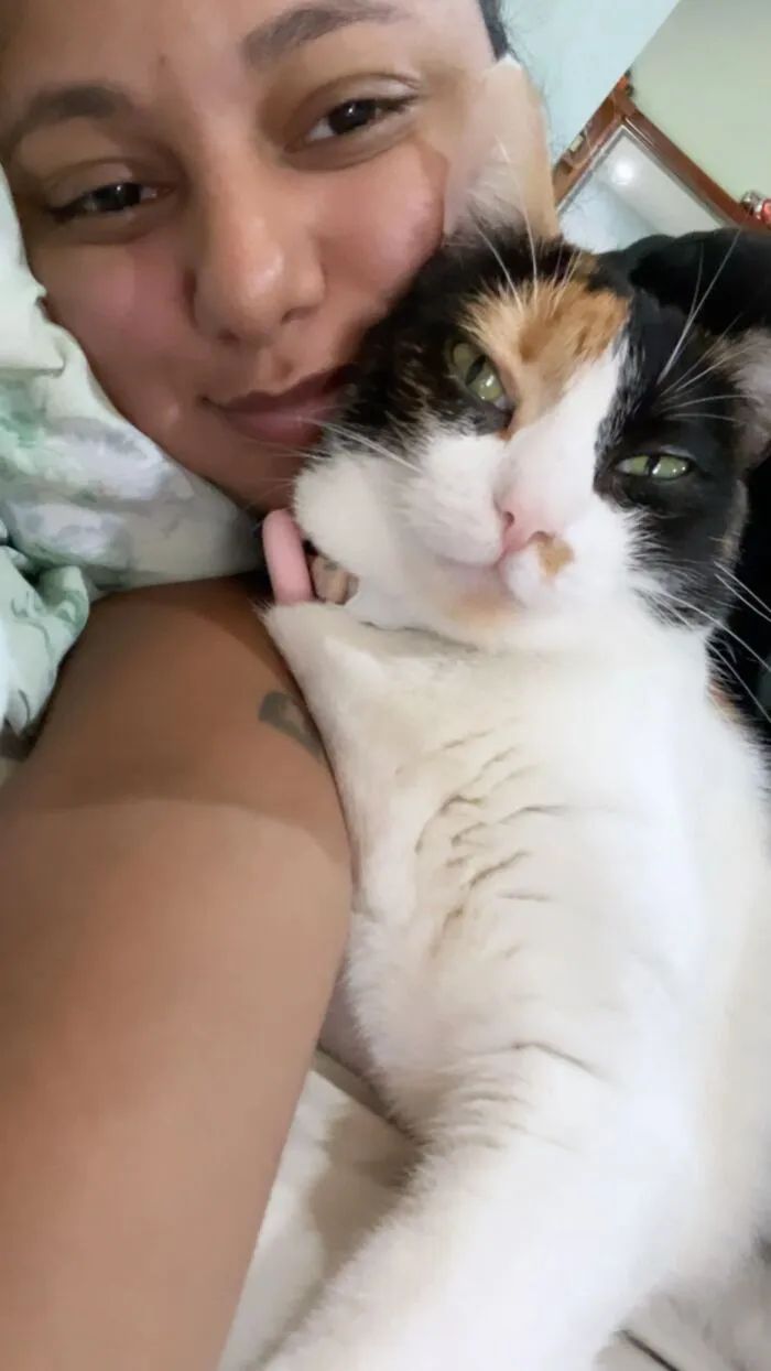 A smiling woman cuddling with her calico cat, showcasing life stories lived alongside their pets.