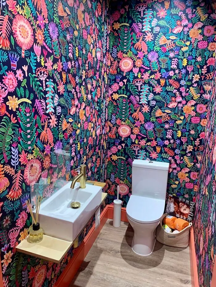 A small bathroom with colorful floral wallpaper after a home makeover