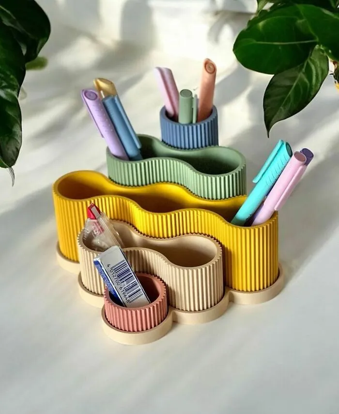Colorful wavy organizers holding pens and office supplies on a desk, made with a 3D printer.