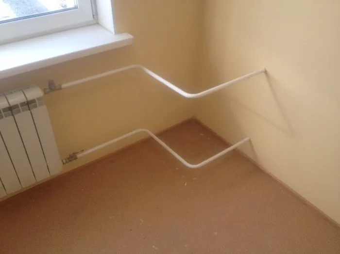 Awkwardly bent heating pipes extending in a zig-zag pattern from a wall corner, showing a home improvement fail.