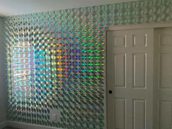 An inventive home makeover with a wall completely decorated using shiny CDs