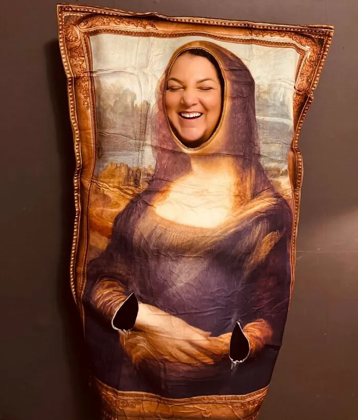 A smiling woman wearing a funny Mona Lisa painting outfit as a low-effort Halloween costume.